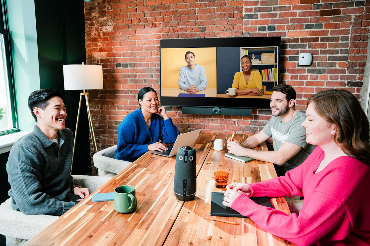 A hybrid team meeting with a Meeting Owl on the conference table and an Owl Bar below the display