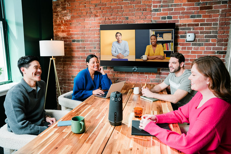 A hybrid team meeting with a Meeting Owl on the conference table and an Owl Bar below the display